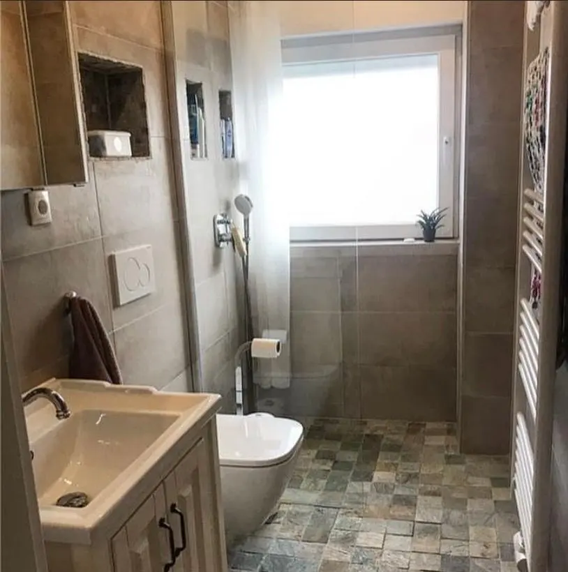 Graues Bad mit bodengleicher Dusche nach der Sanierung